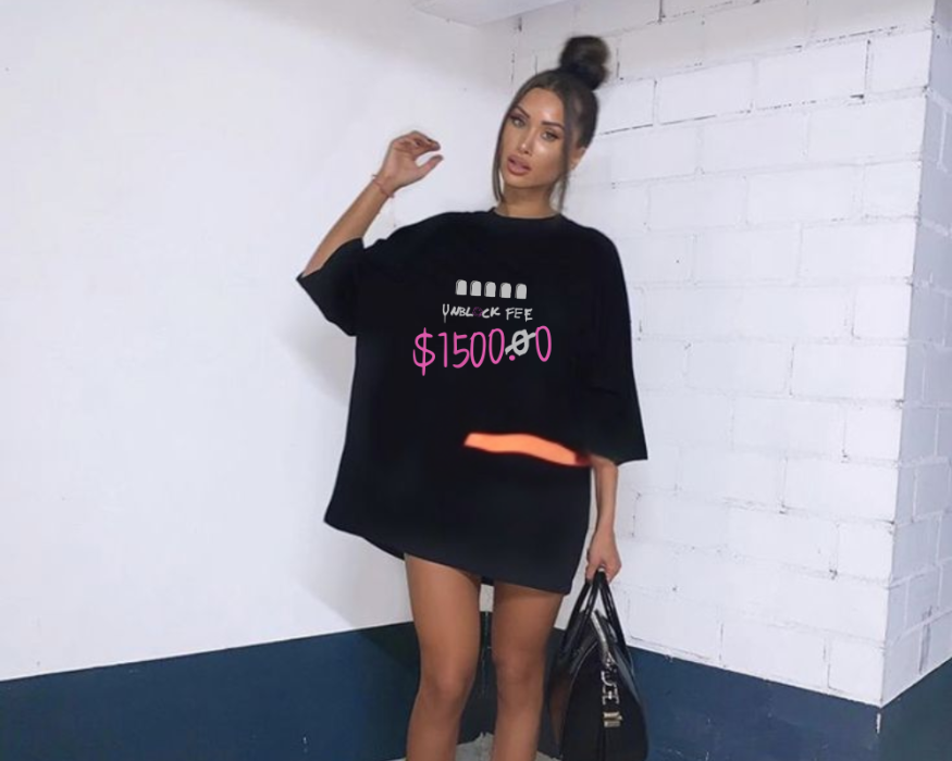 Person wearing a black oversized t-shirt with text and bright orange shoes in a minimal indoor setting.